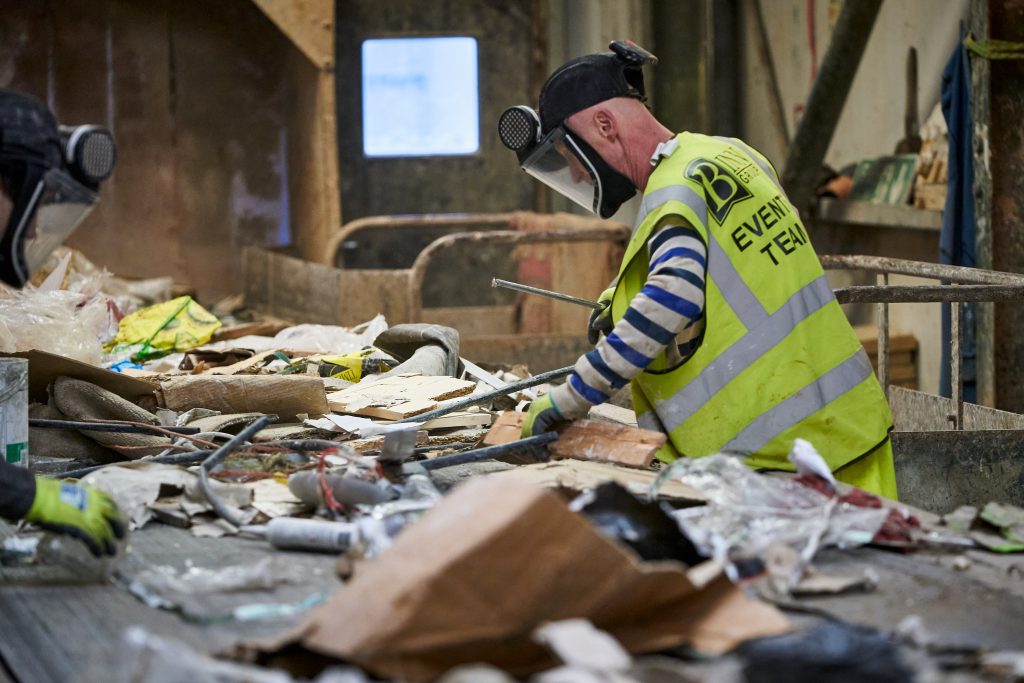Man wearing high vis jacket sorting recycled materials.